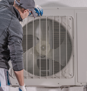 hvac repair man inspecting a large cooling fan