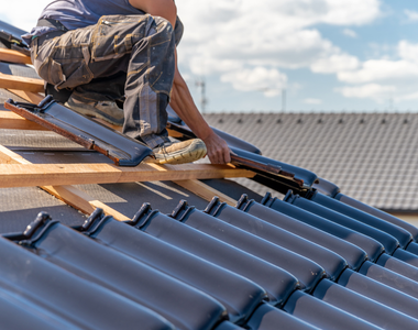 man on a roof adding new metal shingles to a house