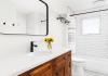 modern farmhouse bathroom with dark oak cabinets, black fixtures, and bright light