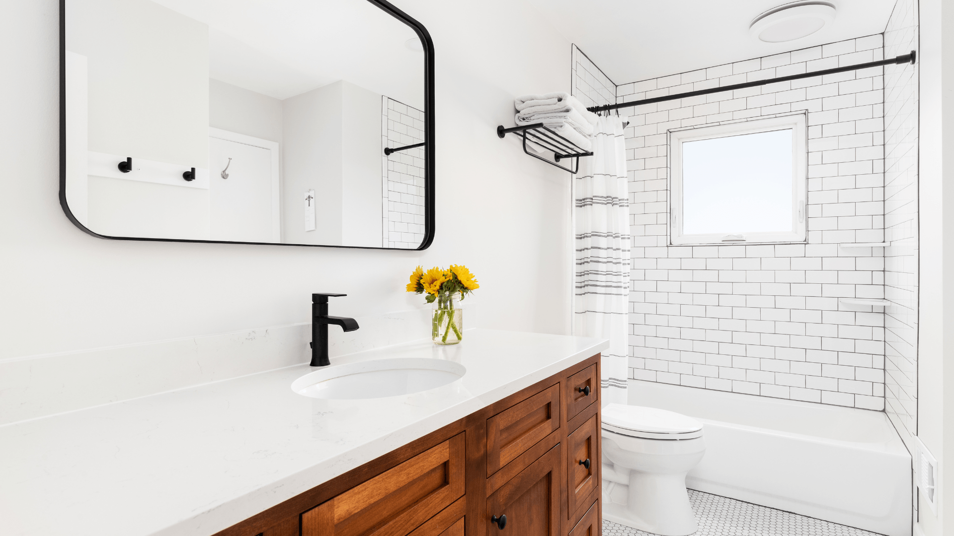 modern farmhouse bathroom with dark oak cabinets, black fixtures, and bright light